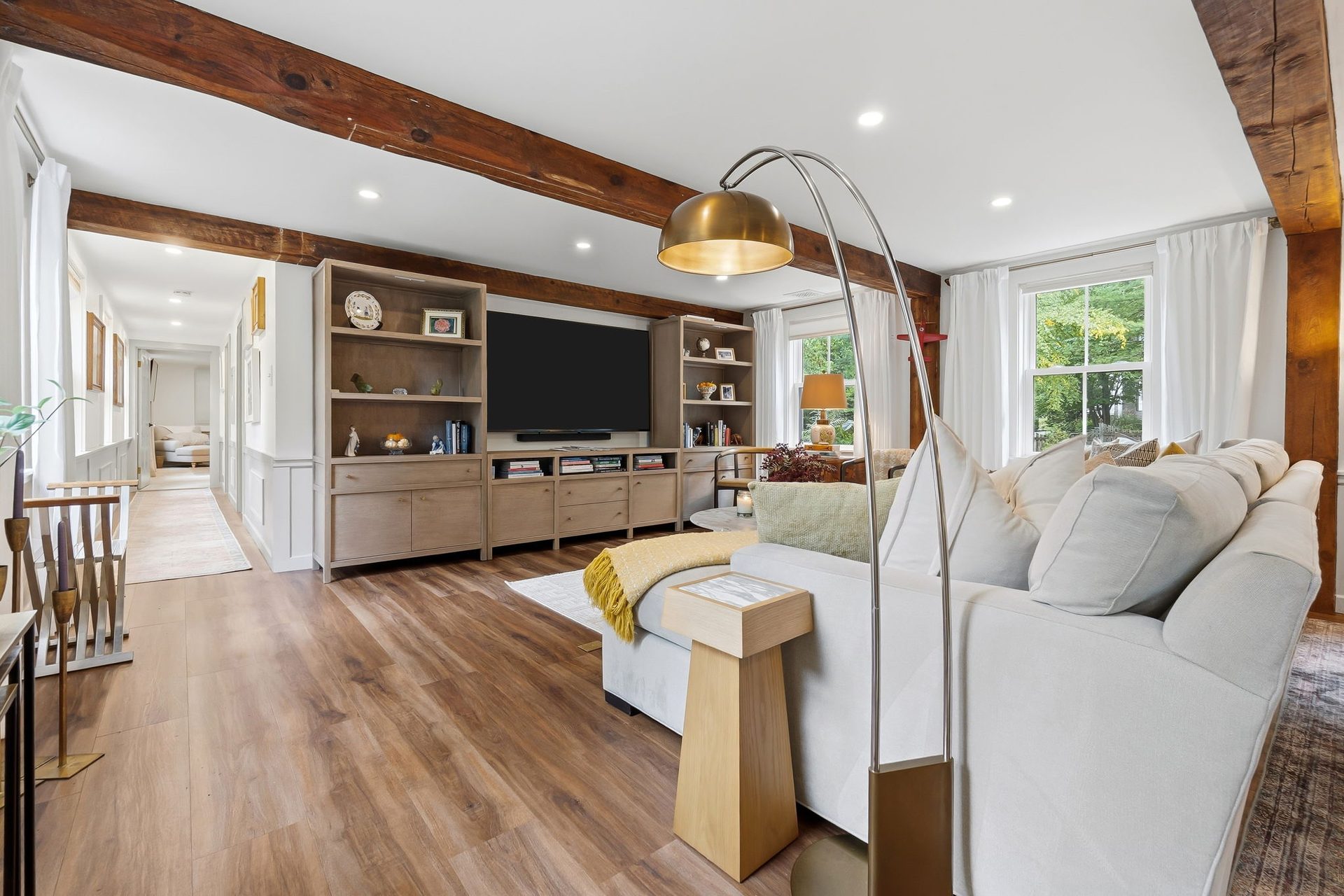 The living room with beams overhead and a built-in media wall